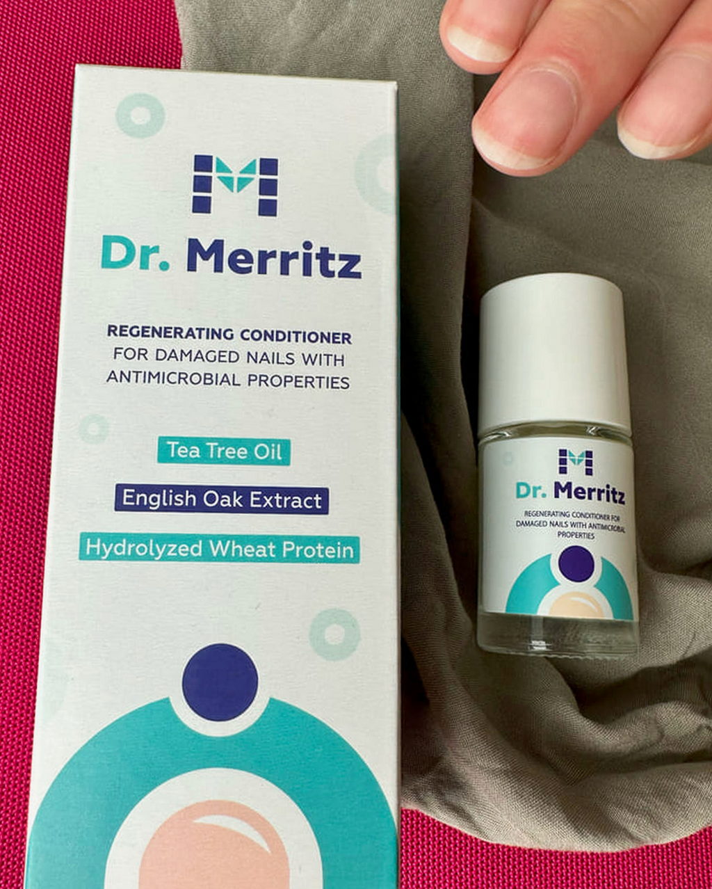 Kartonik i buteleczka Dr. Merritz na tle różowej tkaniny